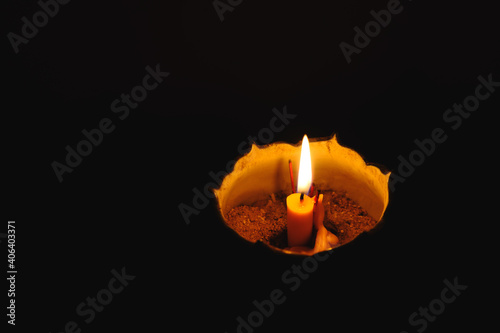 Burning candle in darkness candle light on a joss stick pot