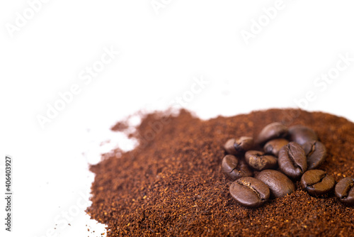 Roasted coffee beans at the top of a pile of ground coffee on an isolated white background. With white area for copy space text.