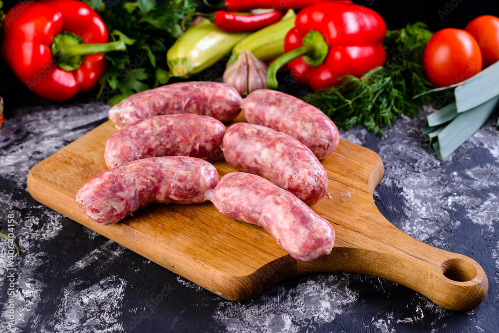 Fresh raw sausage on wooden board, Raw barbecue sausages with spices and vegetables. Top view Freshly made raw breed butchers sausages. Free space