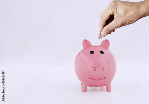 Men hand putting coin to a piggy bank on white background, Saving money concept 