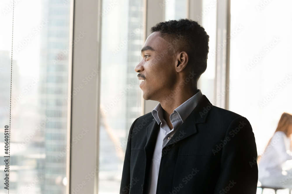 Smiling ethnic businessman in suit look in window distance thinking or pondering of career success. Pensive happy male employee or worker imagine or visualize opportunities. Business vision concept. Smiling ethnic businessman in suit look in window distance thinking or pondering of career success. Pensive happy male employee or worker imagine or visualize opportunities. Business vision concept.