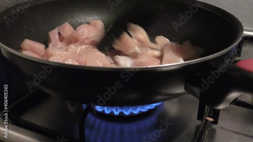 Lean chicken meat being stirred and fried inside pan with black spoon. photo