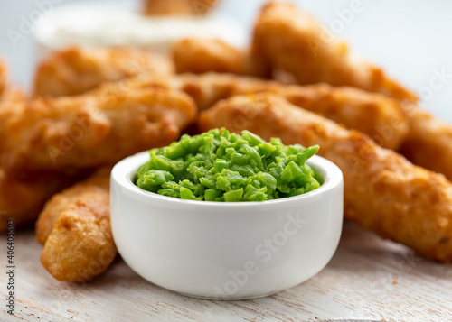 Battered Haddock fish, mini fingers with mashed peas, tartar sauce on white wooden board