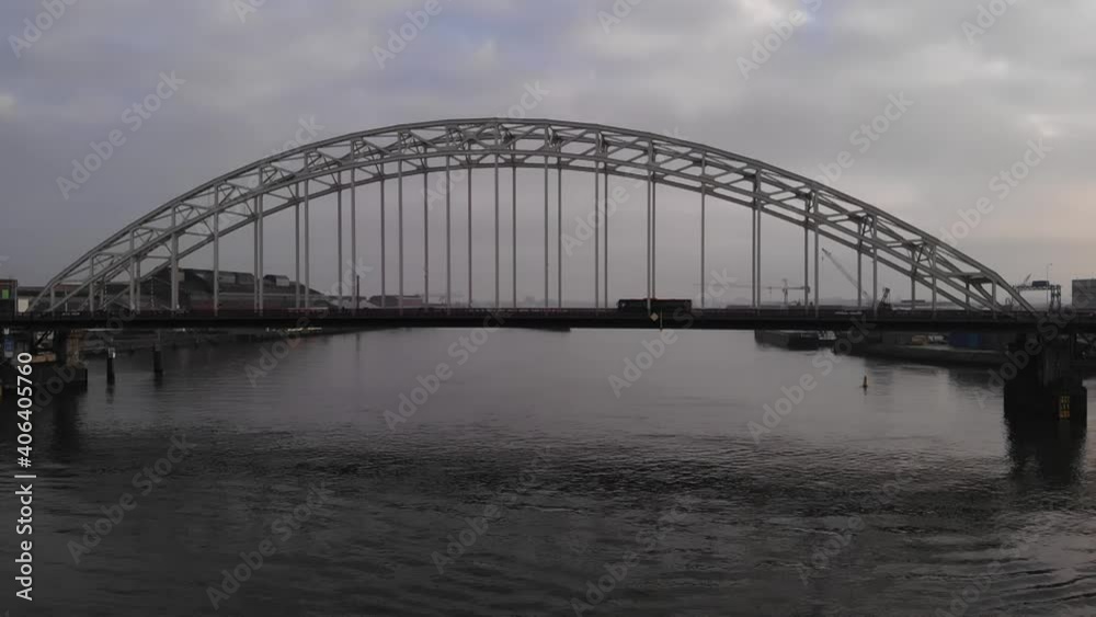 Vehicles Crossing The Arch Bridge Over Noord River In Alblasserdam, Netherlands. - aerial shot Vehicles Crossing The Arch Bridge Over Noord River In Alblasserdam, Netherlands. - aerial shot