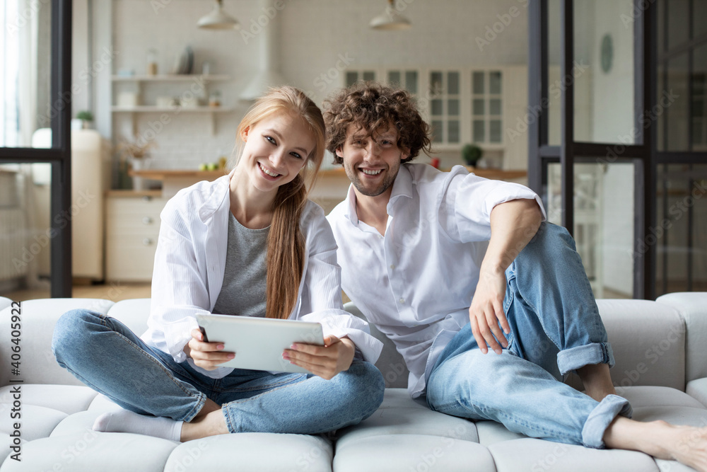 Man and woman relaxing on couch in living room and using digital tablet. Man and woman relaxing on couch in living room and using digital tablet.