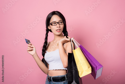 Asian young woman with a lot of money in her hand holding a shopping bag smiling happily on the pink background.