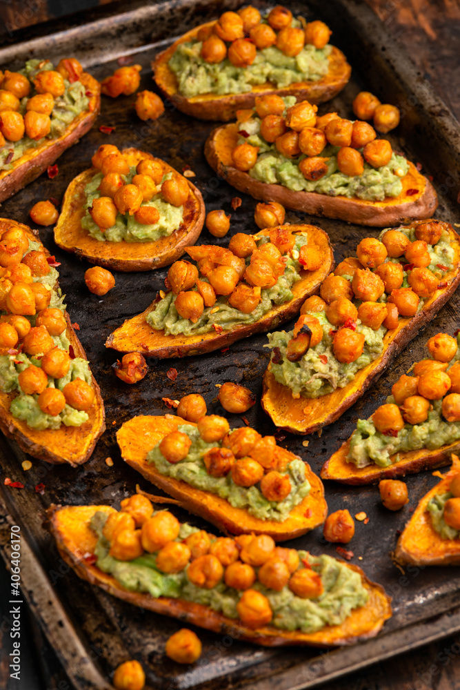 Sweet potato toast loaded with avocado guacamole and baked chickpeas on rustic metal oven-tray