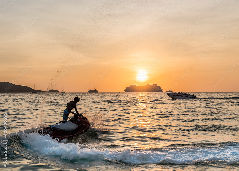 Jet ski against the silhouettes of ships at sunset