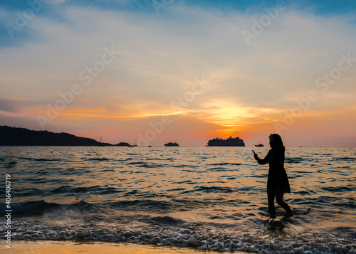 Silhouettes of the girl and ships on the background of the sunset sky in the Andaman sea