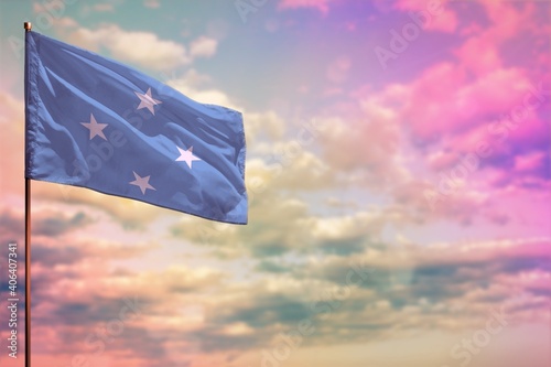 Fluttering Micronesia flag mockup with the space for your content on colorful cloudy sky background.