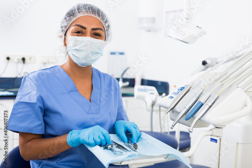 Latin american woman dentist working at modern dental office, preparing special medical tools