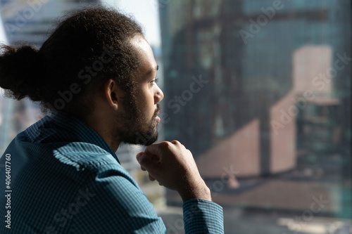 Close up of pensive African American man look in window distance thinking or pondering of future career opportunities. Thoughtful ethnic male make decision or plan. Business vision concept.