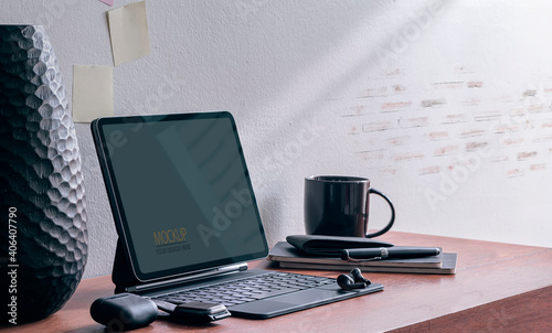 Mockup tablet with magic keyboard and gadget on wooden table.