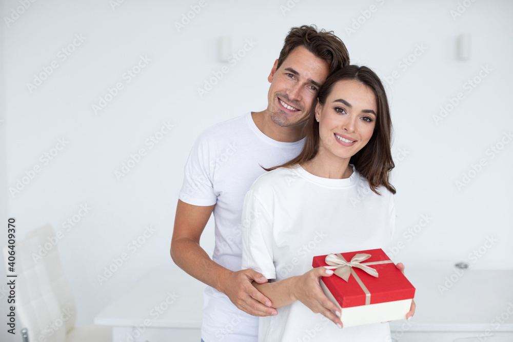 Portrait of a smiling young couple hugging while standing together with gift Portrait of a smiling young couple hugging while standing together with gift