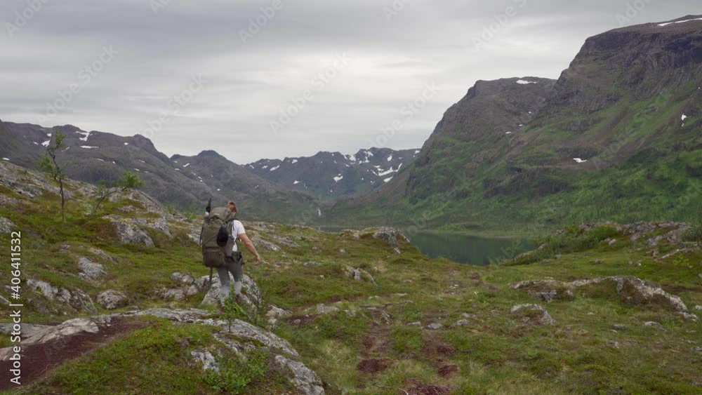 Man With Hiking Bag Trekking In Mountains Of Norway. - wide shot Man With Hiking Bag Trekking In Mountains Of Norway. - wide shot