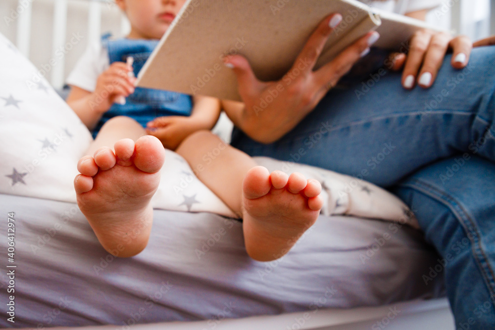 Young mother reads a book to her daughter before bedtime.