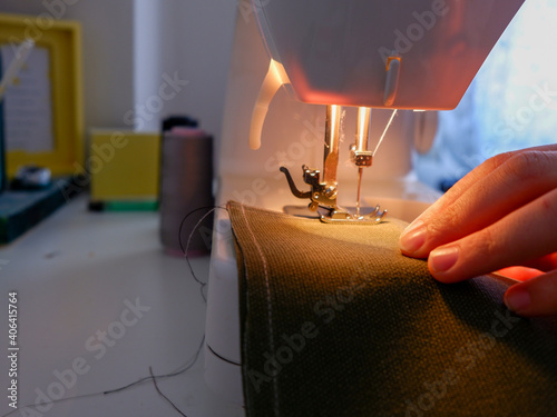 Fototapeta Naklejka Na Ścianę i Meble -  Sewing on sewing machine. Woman sewing at home. Using sewing machine while sewing clothes.