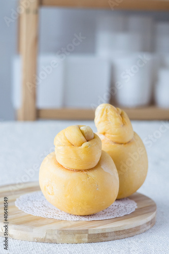 Fresh italian cheese caciocavallo on cutting board on light rustic background, selective focus.