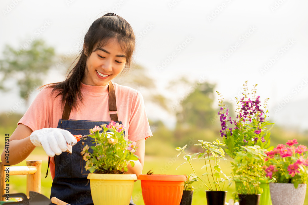 Portrait of smiling young asian woman with glove planting flower in garden at outdoor Portrait of smiling young asian woman with glove planting flower in garden at outdoor