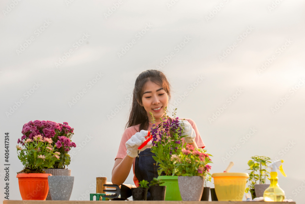 Portrait of smiling young asian woman with glove planting flower in garden at outdoor Portrait of smiling young asian woman with glove planting flower in garden at outdoor