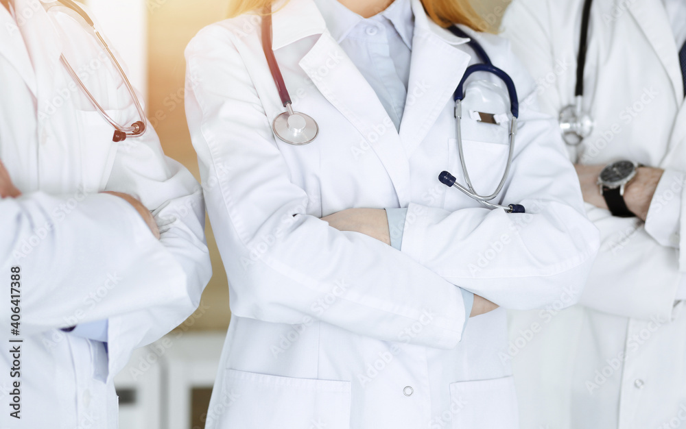 Group of modern doctors standing as a team with arms crossed in hospital office, close-up. Medical help, insurance in health care, best treatment and medicine concept Group of modern doctors standing as a team with arms crossed in hospital office, close-up. Medical help, insurance in health care, best treatment and medicine concept