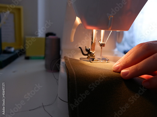 Fototapeta Naklejka Na Ścianę i Meble -  Sewing on sewing machine. Woman sewing at home. Using sewing machine while sewing clothes.Selective focus .