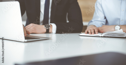 Unknown business people using laptop computer at the desk in modern office. Businessman or male entrepreneur is working with his colleague. Teamwork and partnership concept