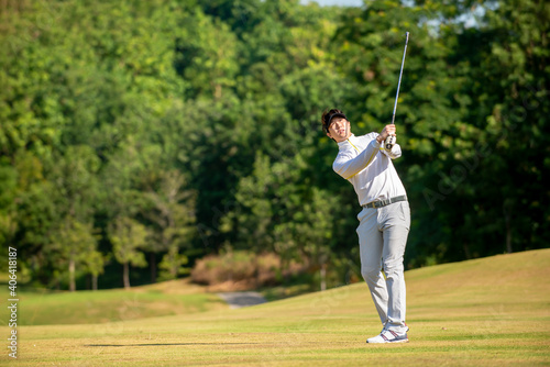 Asian man golfer hitting ball on fairway at golf course