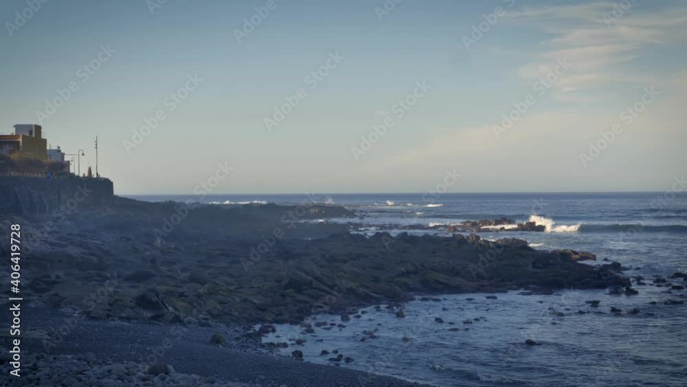 Waves break on the rocky shoreline of Tenerife. Wide view of coast along island paradise vacation and holiday destination. Waves break on the rocky shoreline of Tenerife. Wide view of coast along island paradise vacation and holiday destination.