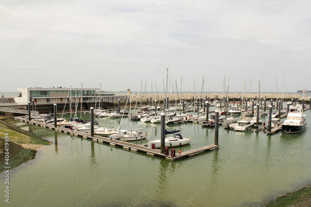 the new marina with yachts and fishing boats in turquoise water in front of a michelin starred restaurant in cadzand, the netherlands
