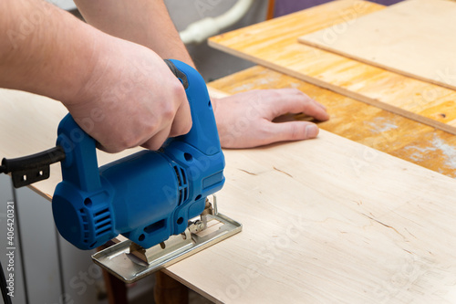 Image of a man hand using electric jigsaw