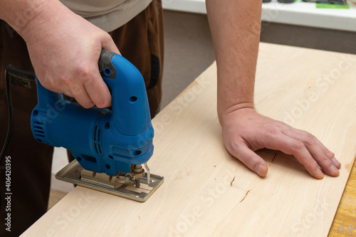 Image of a man hand using electric jigsaw