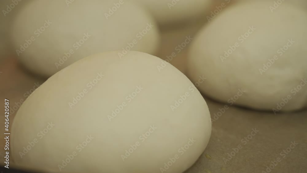 Brushing egg wash over some burger buns dough, ready to be baked in the oven Brushing egg wash over some burger buns dough, ready to be baked in the oven