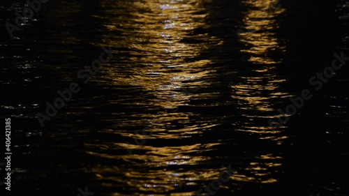 Light of street lanterns reflected in river water channel late in the night.