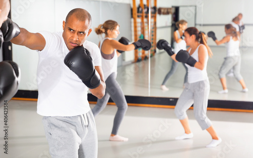 Portrait of diligent serious positive glad females and males training in boxing gloves