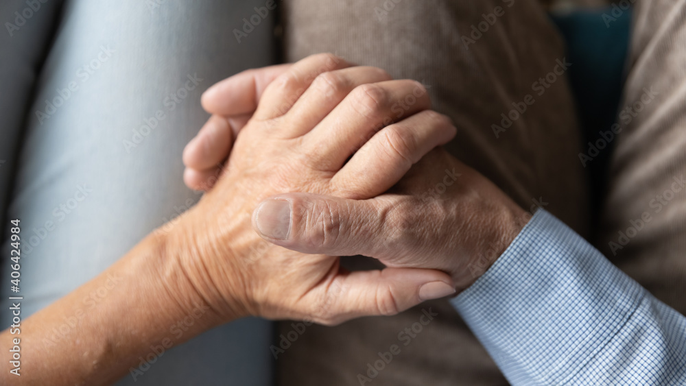 Top above close up view loving affectionate old senior married family couple holding hands, enjoying sweet tender moment together at home, showing support and care to each other, relations concept.