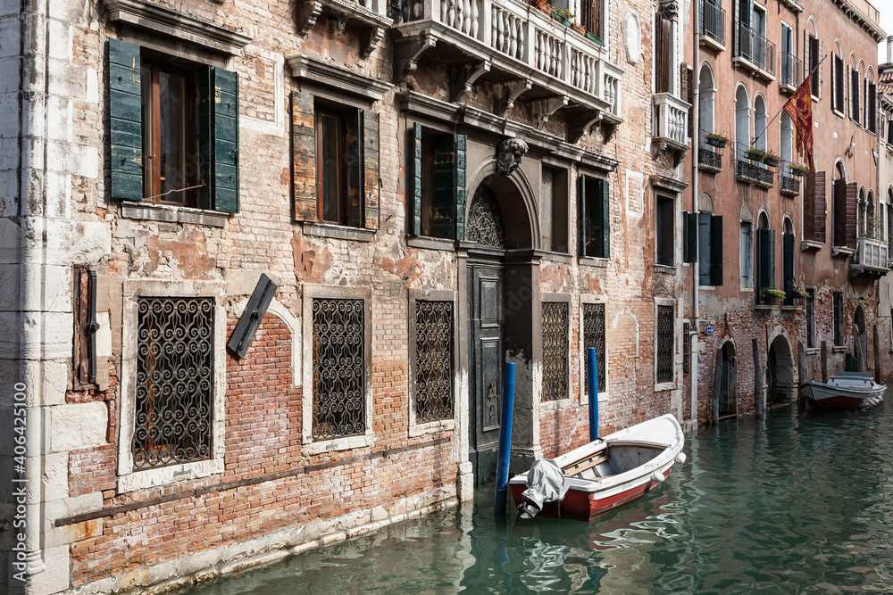 Typical venetian canal with a boat outside an old palazzo building, Venice, Italy