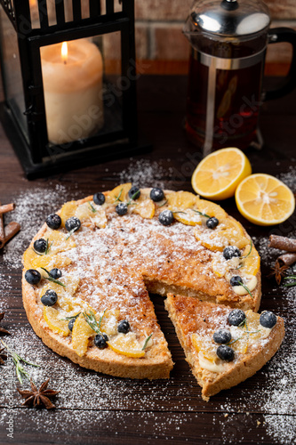 Lemon tart as a christmas treat in festive atmosphere with candles and snow around