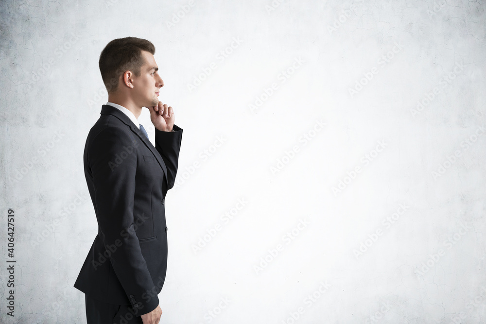 Pensive young European businessman thinking near concrete wall Pensive young European businessman thinking near concrete wall