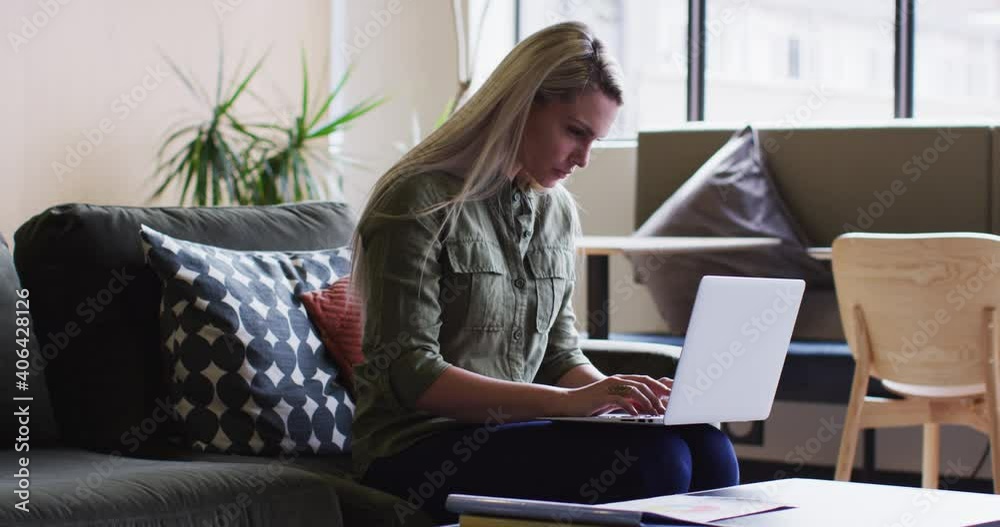 Caucasian businesswoman sitting and using her laptop in modern office