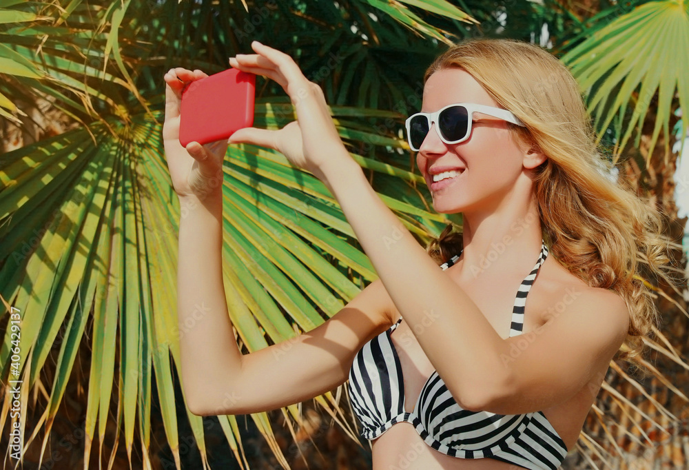 Summer portrait of happy smiling woman taking selfie picture by smartphone on a beach, palm tree background Summer portrait of happy smiling woman taking selfie picture by smartphone on a beach, palm tree background
