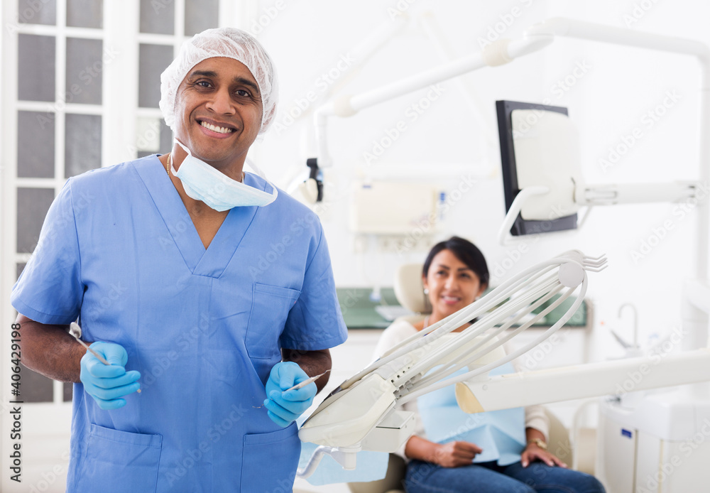 Obraz premium Portrait of positive dentist in dental office on the background of patient