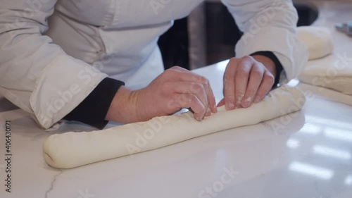Chef forming bread dough on cooking table in the restaurant. Hands close up. Slow motion. photo
