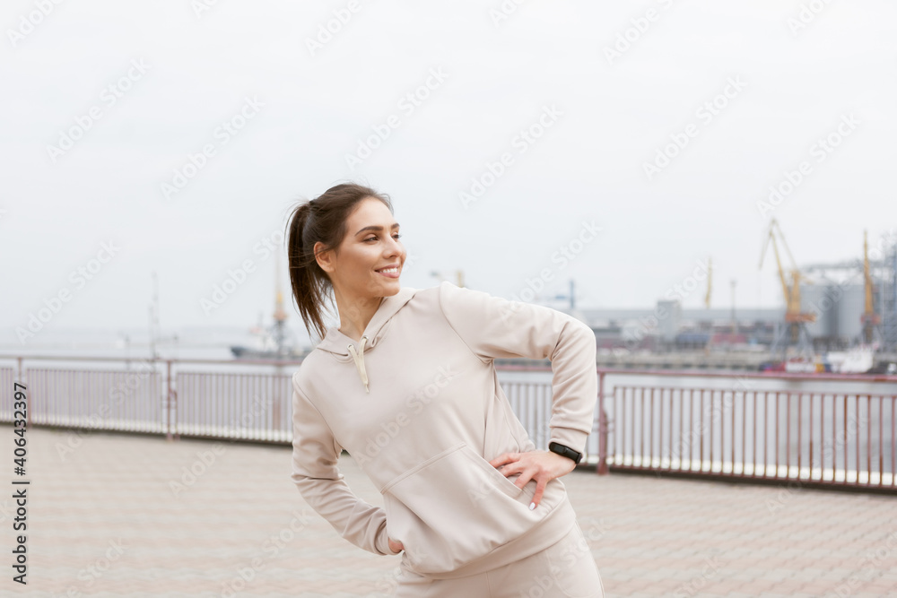 Young fit slim woman doing warm-up exercise before training outdoors