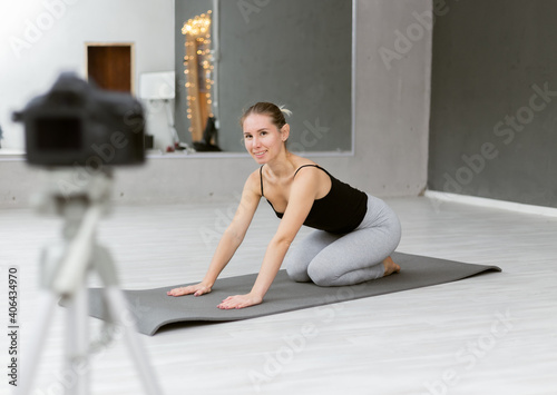 Fit woman yoga coach indoor records vlogs, using camera on tripod. Online learning concept, online classes