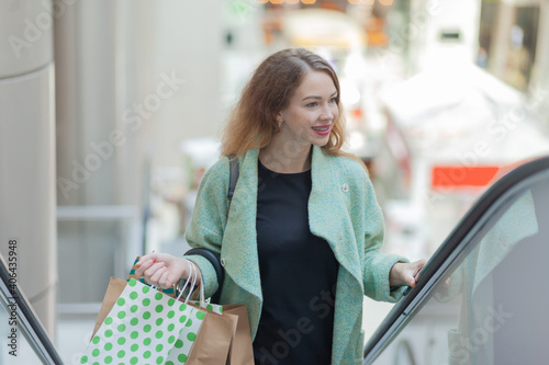 Attractive shopping woman with shopping bags in hand climbs the escalator in the mall photo