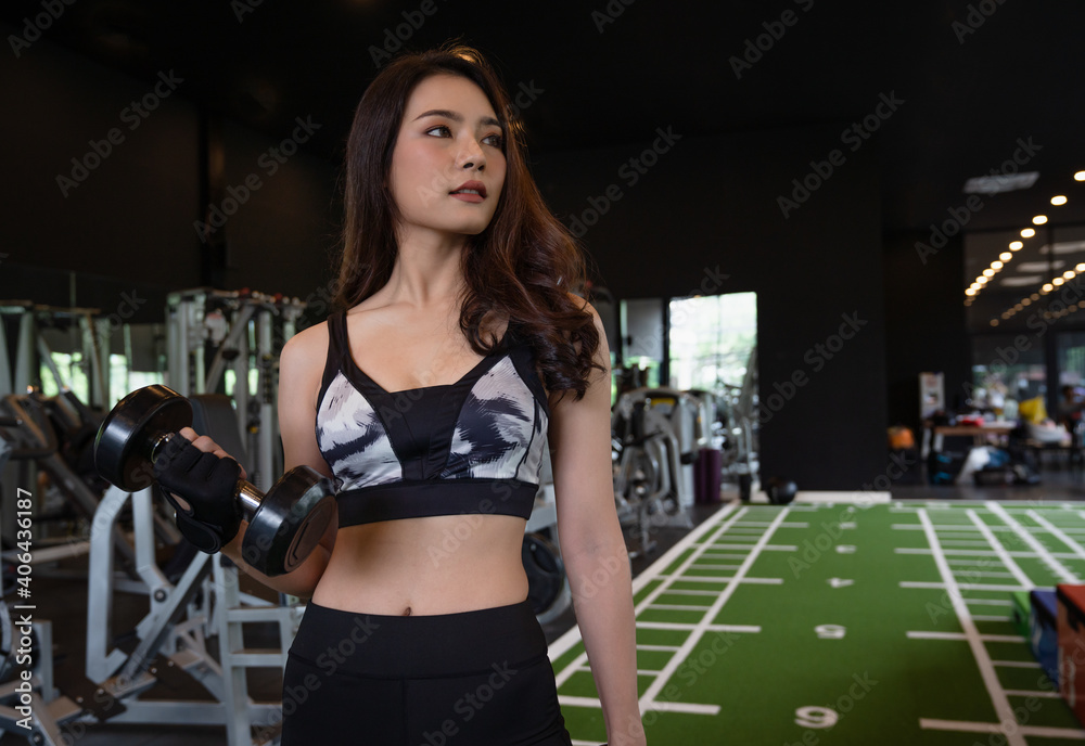 Beautiful asian young woman workout training and exercise with dumbbell weights at fitness gym sport club