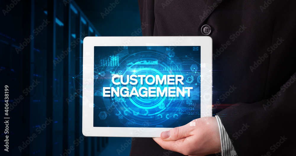 Young business person working on tablet and shows the inscription: CUSTOMER ENGAGEMENT, business concept Young business person working on tablet and shows the inscription: CUSTOMER ENGAGEMENT, business concept
