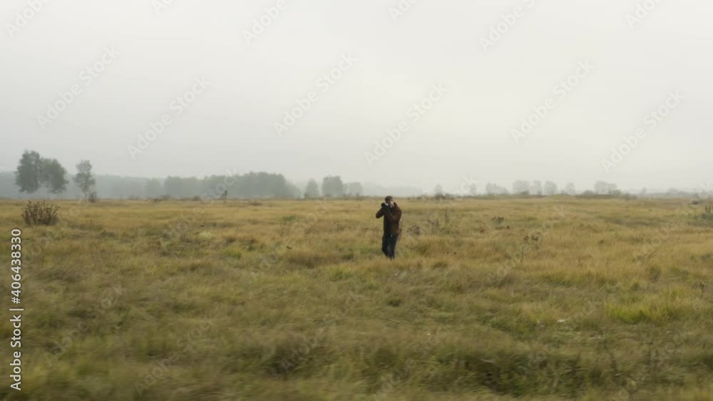 Male documentarist taking pictures in a foggy grassland,autumn,Czechia. Male documentarist taking pictures in a foggy grassland,autumn,Czechia.