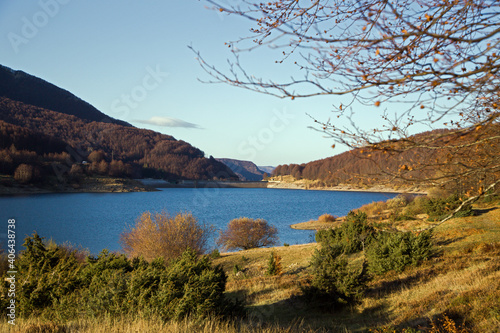 Italian mountain pass with lake and autumn foliage forest, Lagastrello photo